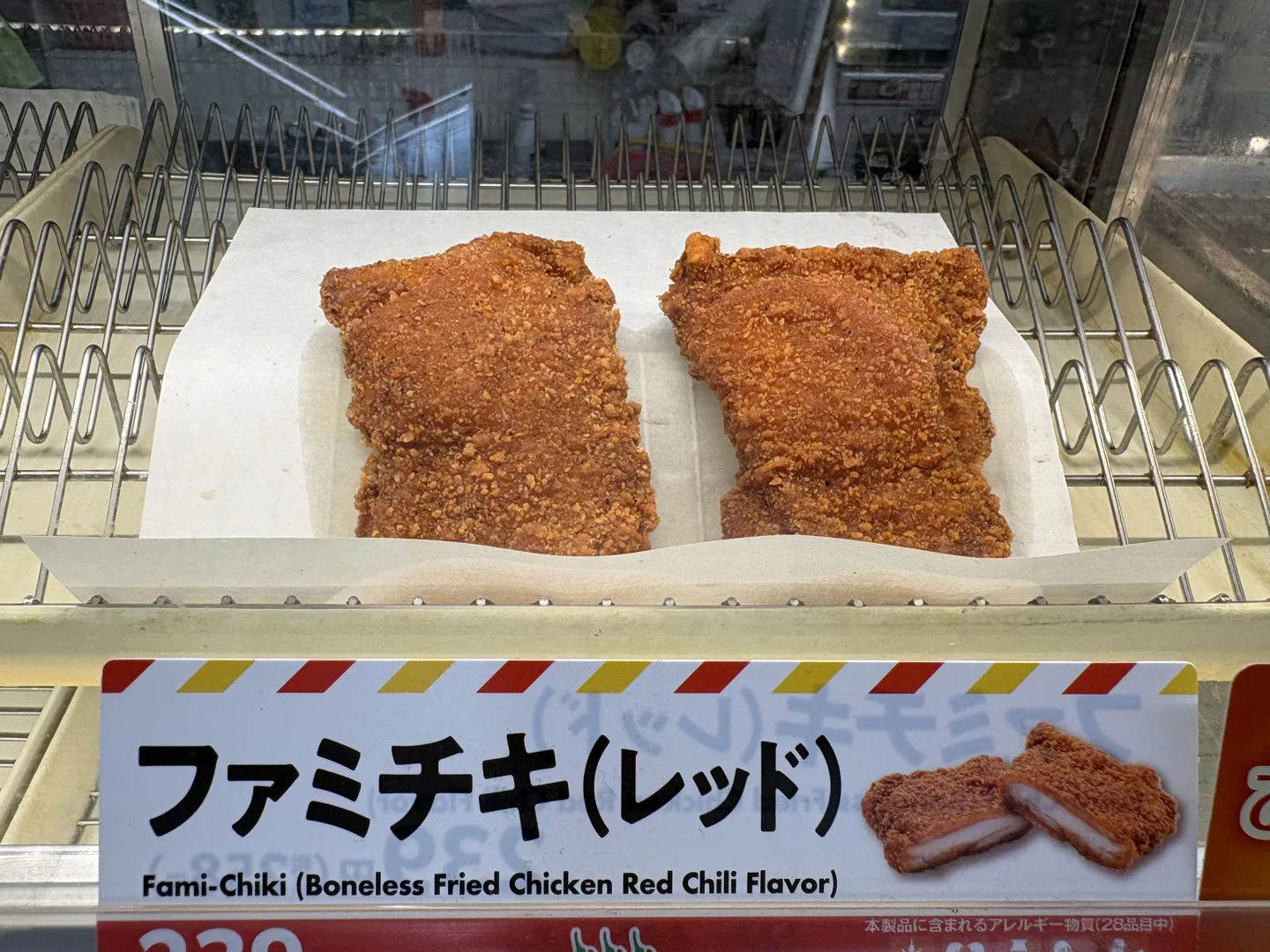 Two pieces of Famichiki Red in a heated display above a Japanese and English product sign