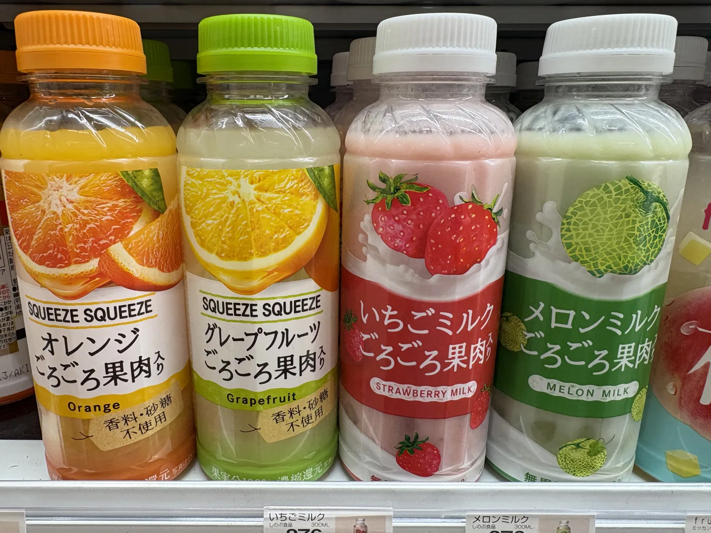 Orange and grapefruit SQUEEZE SQUEEZE drinks beside strawberry milk and melon milk bottles